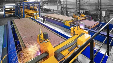 A production line in which two cutting systems are connected with an automated pallet changing system and a sheet metal rack storage system: This configuration enables 24/7 operation at the Dutch shipyard Neptune Shipyards.